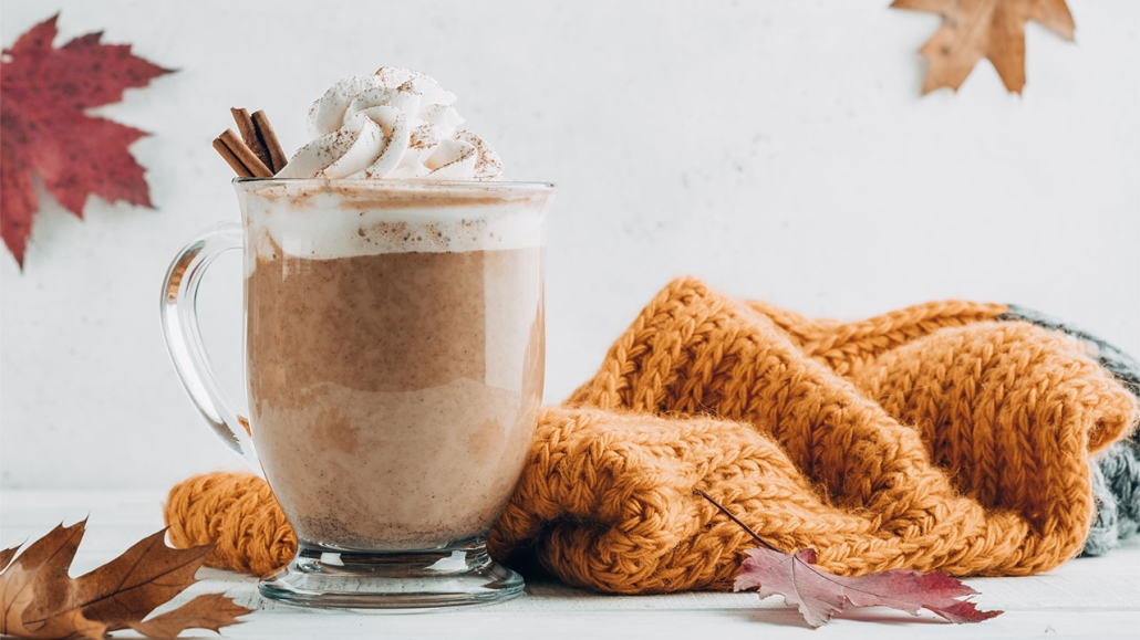 Pumpkin spice latte in a glass mug with cinnamon with Autumn decoration