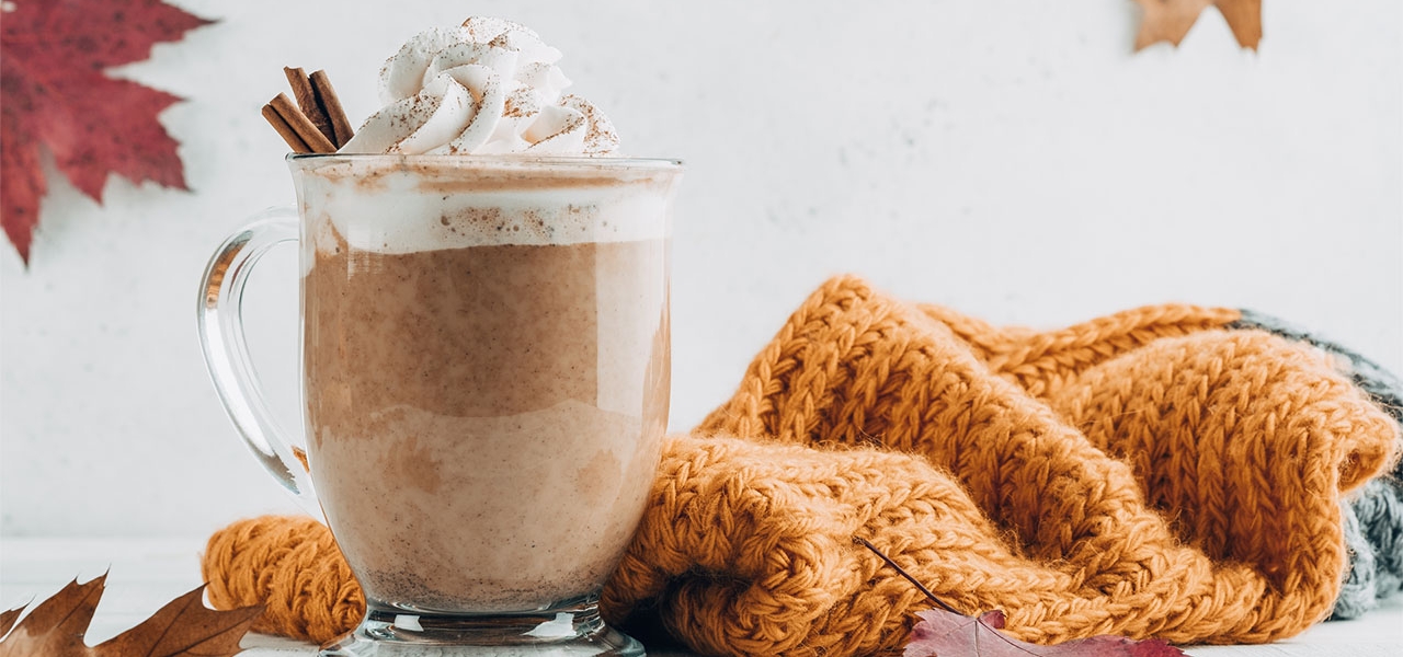 Pumpkin spice latte in a glass mug with cinnamon with Autumn decoration