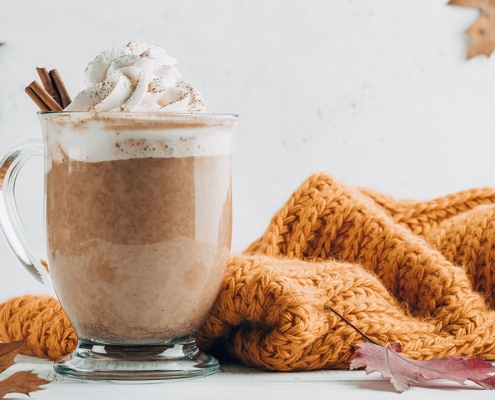 Pumpkin spice latte in a glass mug with cinnamon with Autumn decoration